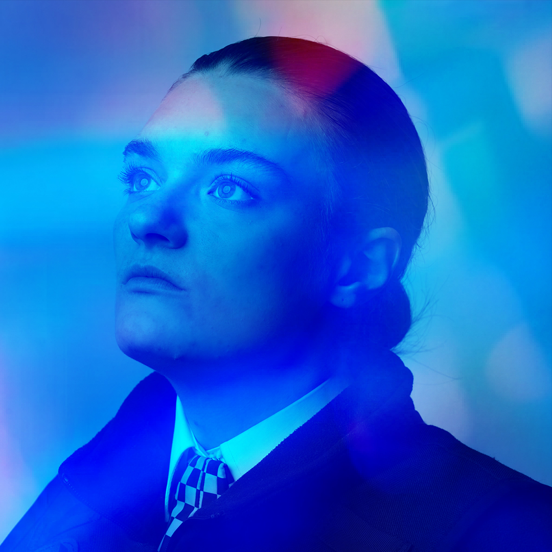 Alright Sunshine by Isla Cowan. A photo of a girl looking up towards her left. She's wearing a police uniform and has her hair tied in a bun.